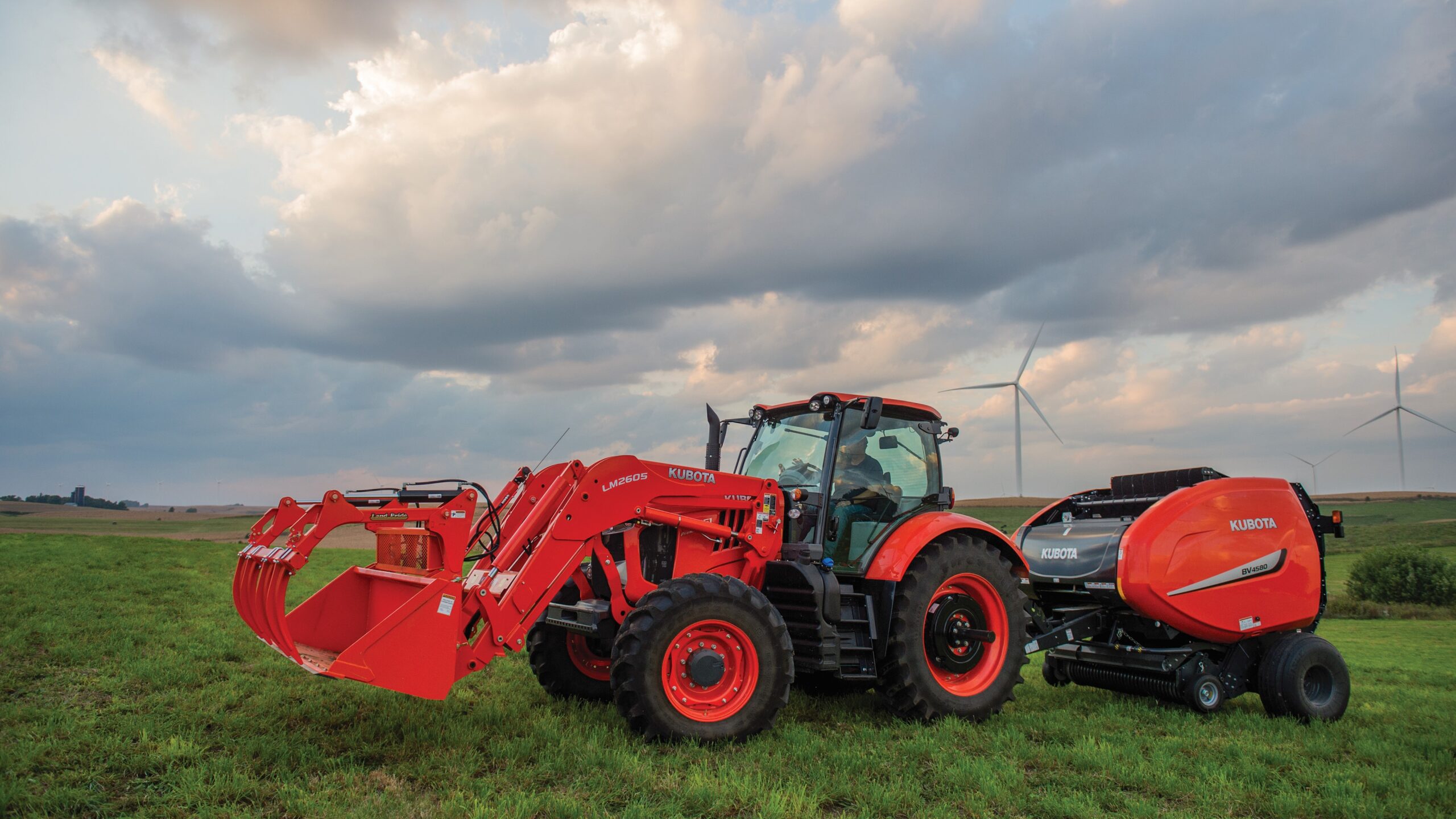 Kubota M7 tractor baling hay in field